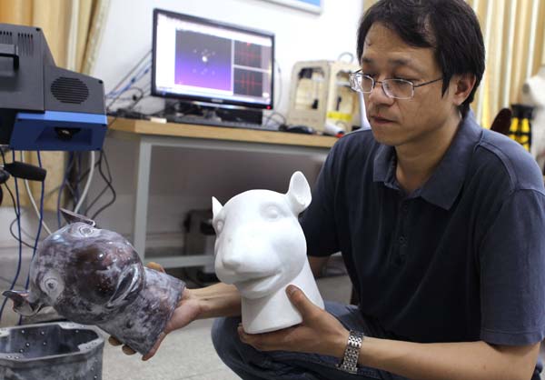Zhou Gang, a doctoral candidate in material science at Huazhong University of Science and Technology, holds an animal head sculpture in his right hand and a replica made through 3-D printing in his left. Photo by Guan Xin / China Daily 3-D printing adds wings to aviation