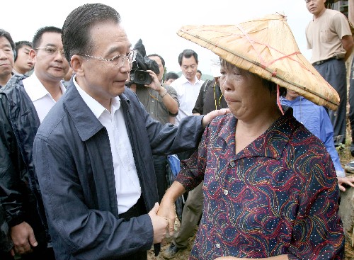 Chinese Premier Wen Jiabao talks to a farmer at a flood-hit village in Longyan City, East China��s Fujian Province, June 27, 2006. Since mid-May, Fujian has been devastated by typhoon- and rainstorm-caused floods, leaving at least 25 deaths and five missing and causing enormous financial losses.[Ma Zhancheng/Xinhua]