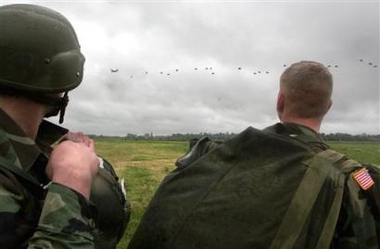 Comrades watch as American parachutists jump over Sainte-Mere-Eglise, northern France, Sunday, June 5, 2005, to commemorate the Allied D-Day landings of World War II. Rain dampened plans for about 150 military parachutists, with Germans taking part for the first time, to leap over the first Normandy town freed from the Nazi grip on June 6, 1944. (AP
