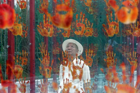 An elderly man who participated in the fight against the Japanese aggression looks at handprints on a wall at a museum in Chengdu, Southwest China's Sichuan Province, September 3, 2006. [Yao Yuan/Chengdu Commercial News]