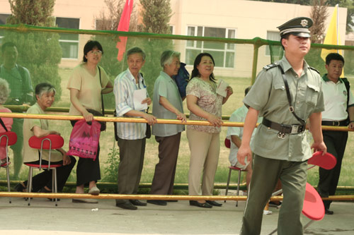 A security man carries a charir at the venue for a vote on demolishment and reconstruction of old buildings in Juixiaqiao Sub-district in Beijing, June 9, 2007. Local government and the real estate developer jointly organize the vote on Saturday to see if majority residents of over 5000 families accept the new compensation policy after failed attempts to reach an agreement through other ways. Both notary officials and supervisors are invited to monitor the vote that runs from 9 a.m. to 9 p.m. at six ballot booths. [Sun Yuqing/www.ming7.cn]