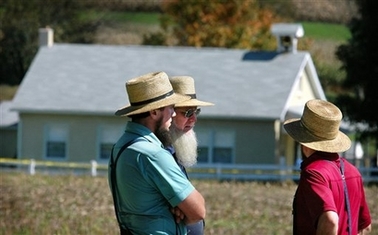 Neighbors gather near a schoolhouse, seen in background, Monday, Oct. 2, 2006, where police say a gunman shot several people in Nickel Mines, Pa. A 32-year-old milk truck driver took about a dozen girls hostage in the one-room Amish schoolhouse Monday, barricaded the doors with boards and killed at least three girls and apparently himself, authorities said. (AP