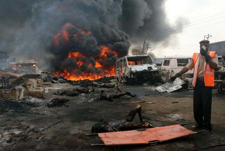 A rescue worker covers his face as he calls for help to remove a burnt corpse from the scene of a gas pipeline explosion as other bodies lie in the background near Nigeria's commercial capital Lagos December 26, 2006. Hundreds of people were burned alive on Tuesday when fuel from a vandalised pipeline exploded in Nigeria's largest city, Lagos, emergency workers said. Crowds of local residents went to scoop up petrol using plastic containers after an armed gang punctured the underground pipeline overnight to siphon fuel into road tankers.