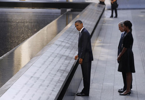 US President Barack Obama touches the names of victims engraved on the side of the north pool of the World Trade Center site as former President George W Bush, first lady Michelle Obama and former first lady Laura Bush (obscured) look on during ceremonies marking the 10th anniversary of the 9/11 attacks on the World Trade Center, in New York Sept 11, 2011. Mourning for 9/11 victims