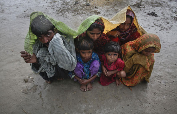 Family members, displaced by floods, use a tarp to escape a monsoon downpour while taking shelter at a make-shift camp for flood victims in the Badin district in Pakistan's Sindh province Sept 14, 2011. 300,000 homeless due to flood in Pakistan