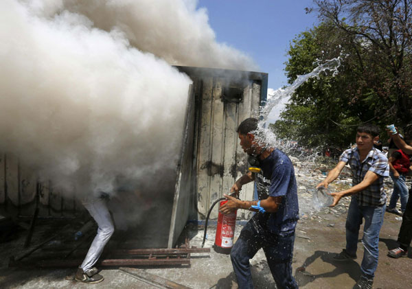 Anti-government protesters try to extinguish a burning container in Istanbul's Taksim square June 4, 2013. Turkish deputy PM seeks to calm protests